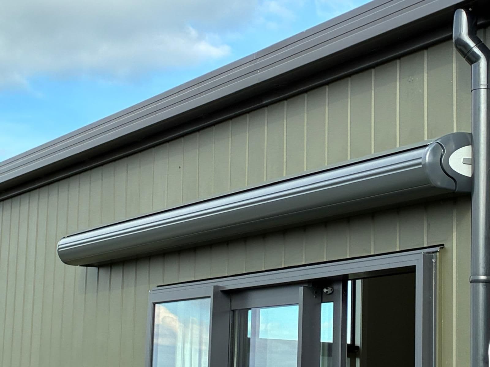 Compact cassette of a folding arm awning mounted above a window