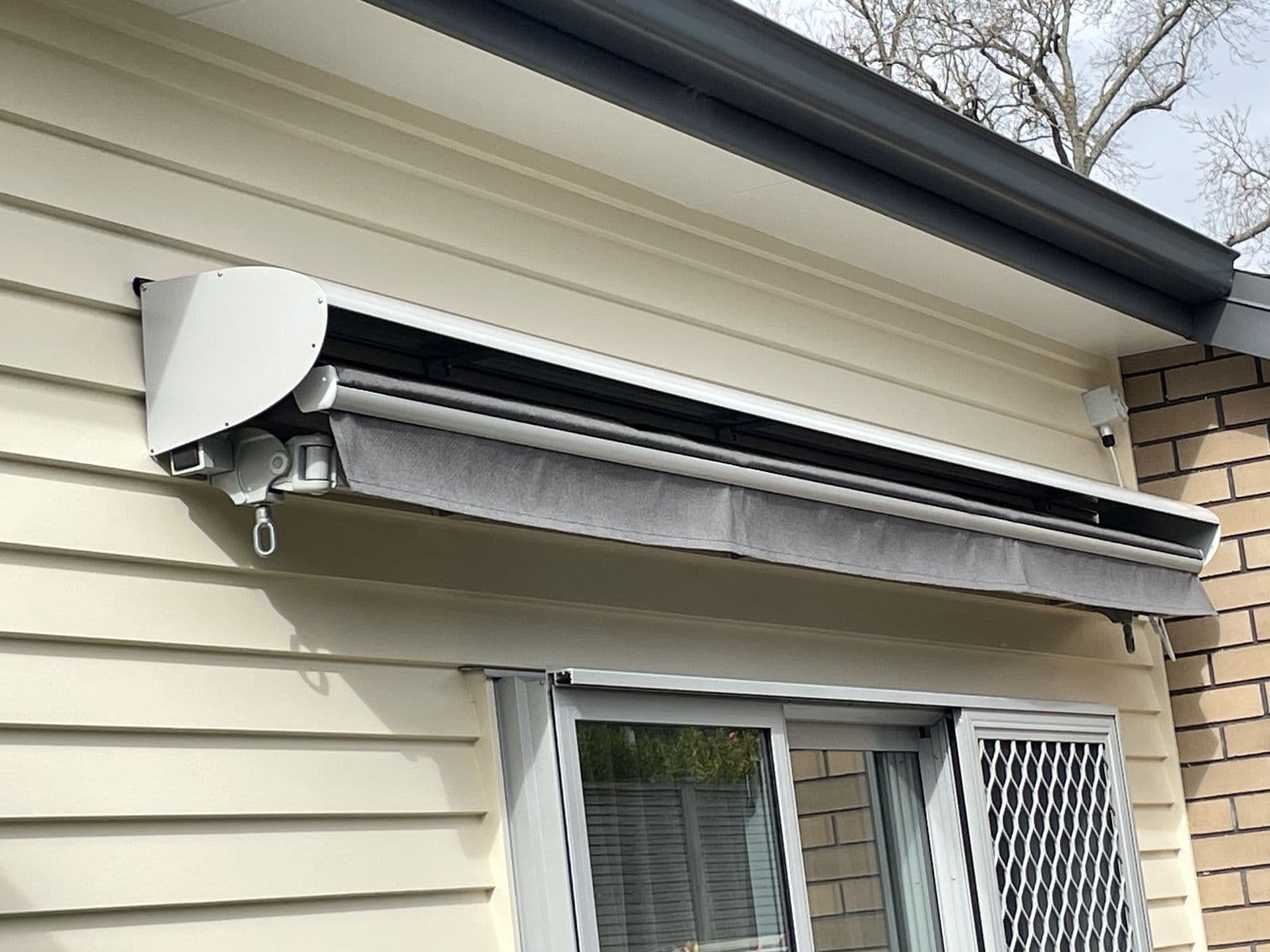 Retracted folding arm awning cassette above a window