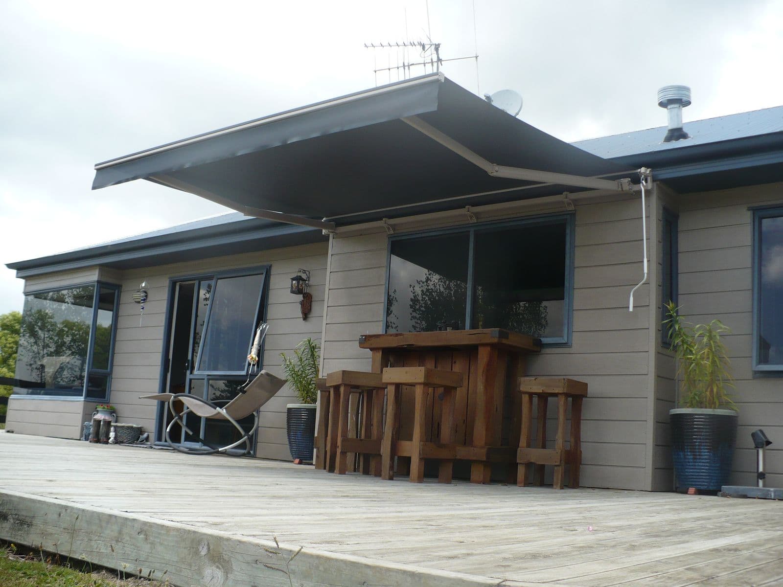 Folding arm awning shading a home’s deck and bar setting