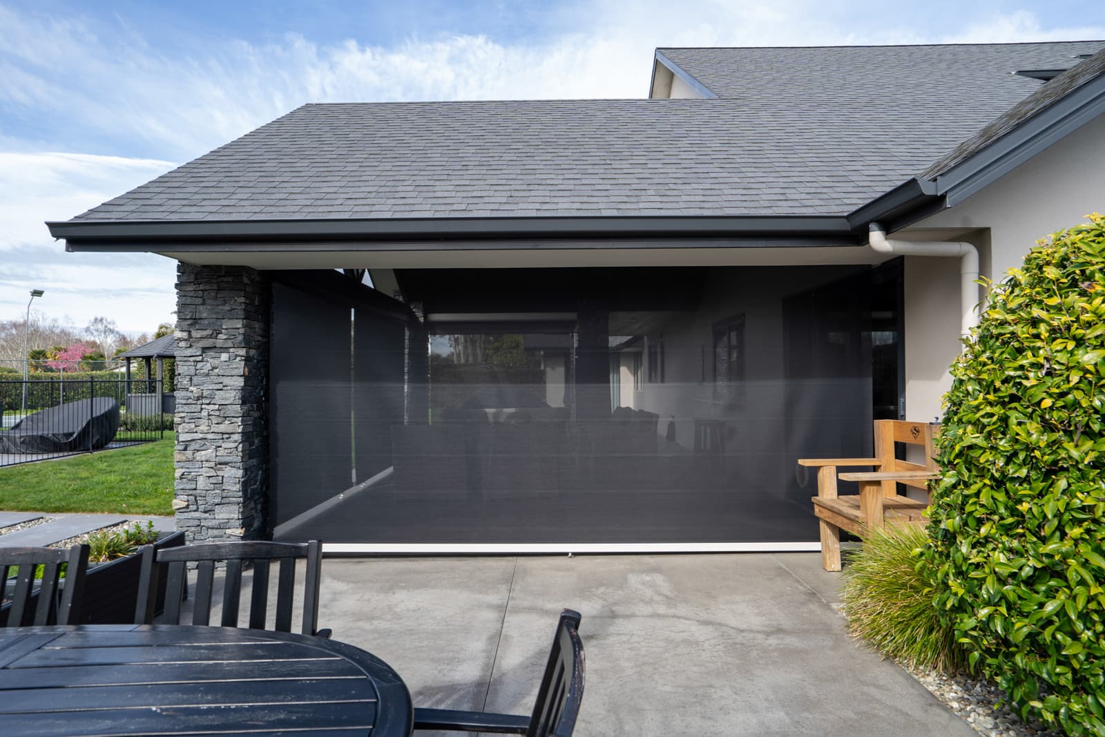 Omni Lite outdoor screen blind lowered over a covered patio