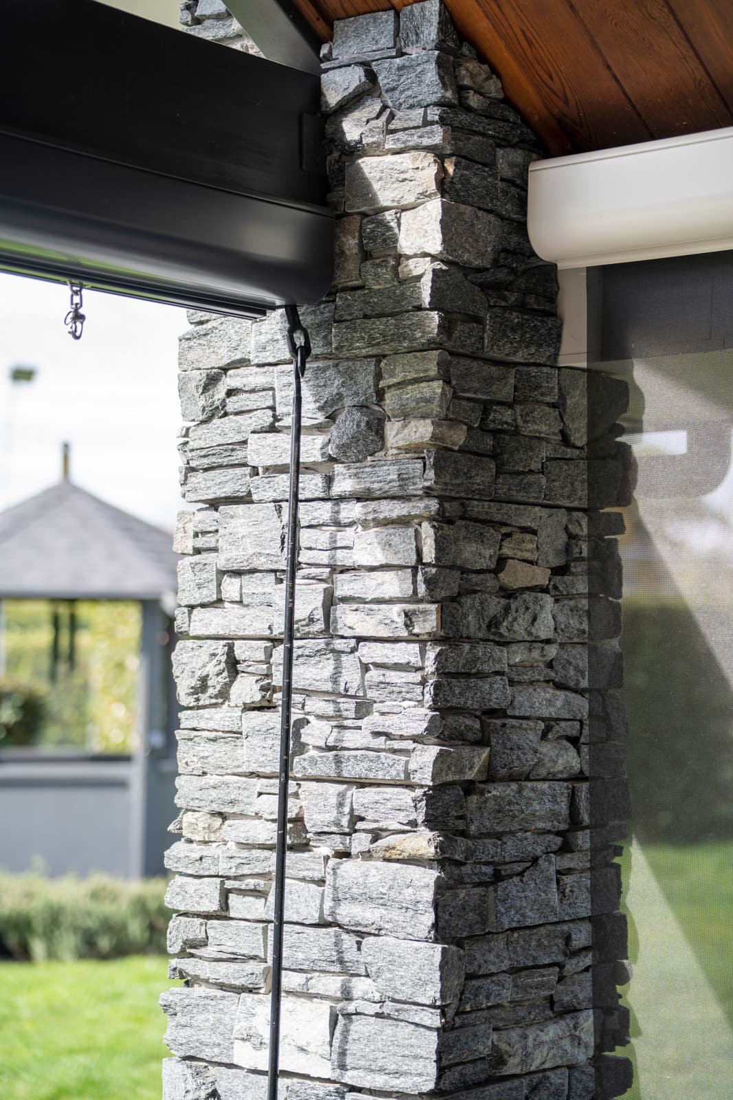 Omni Lite outdoor blind guide cable running down a schist stone column