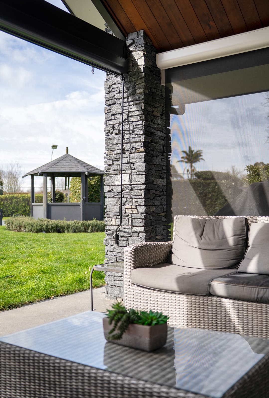 Omni Lite screen blinds beside an outdoor lounge with a garden gazebo view