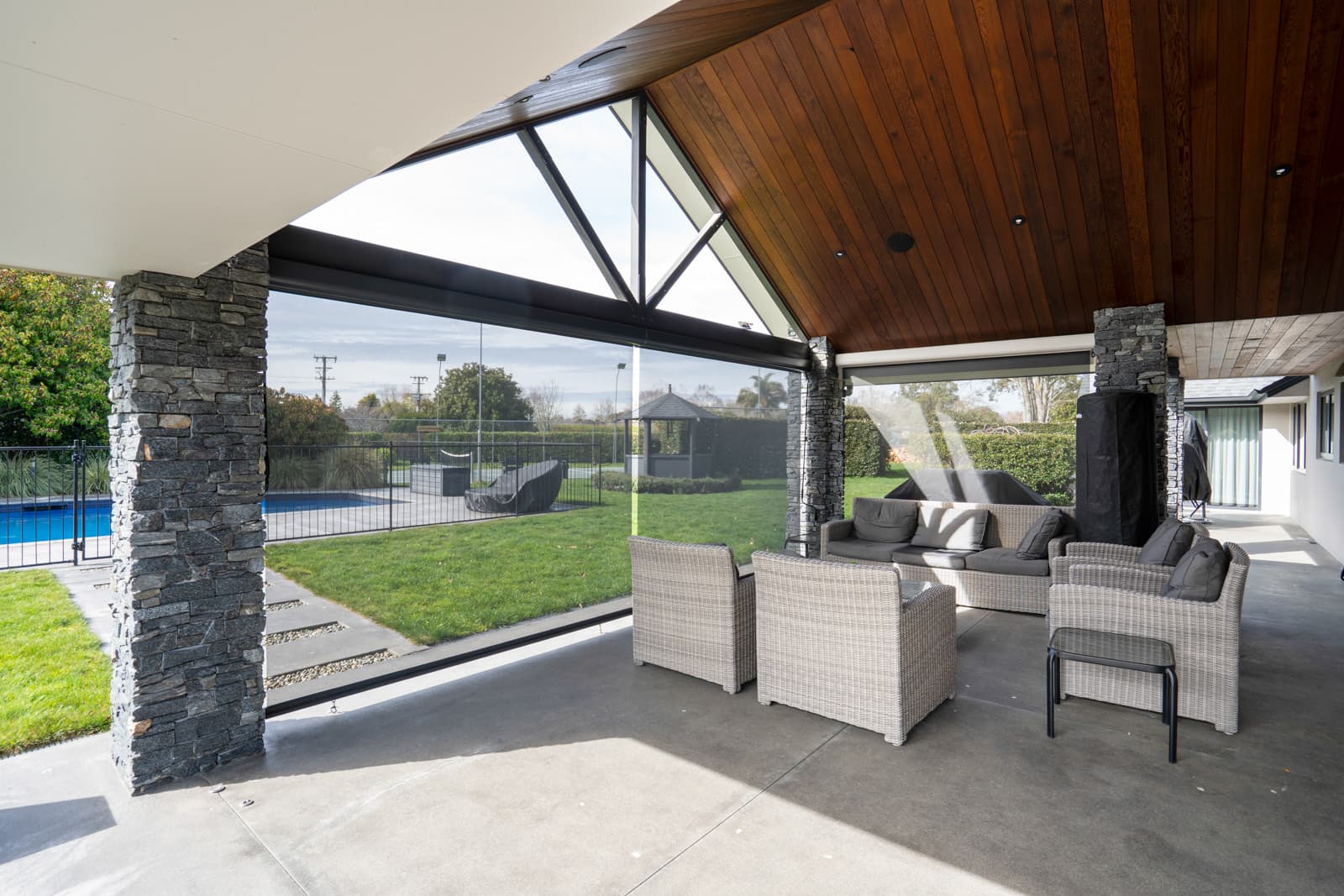 Omni Lite screen blinds enclosing a cedar-lined outdoor lounge beside a pool