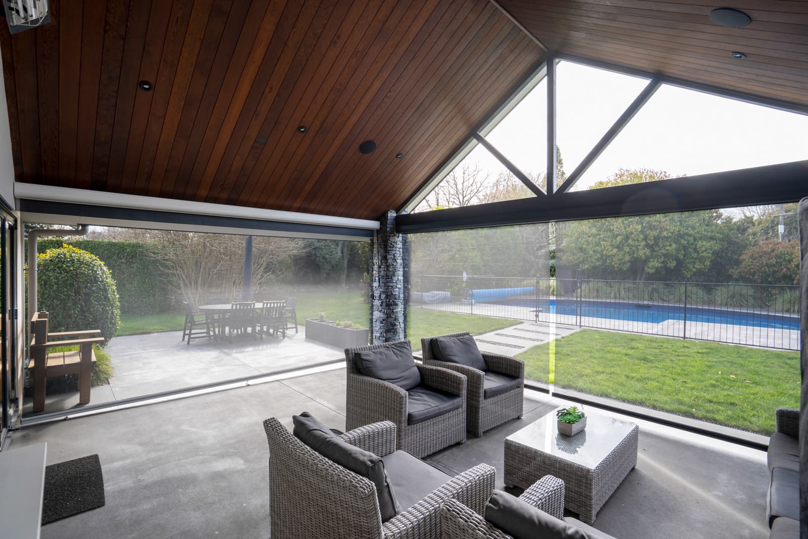 Charcoal Omni Lite screen blinds sheltering a poolside outdoor room