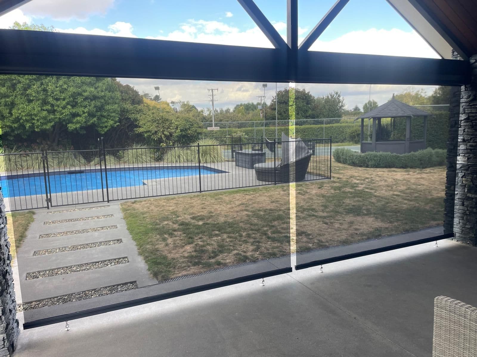 Omni outdoor screen blinds on a covered patio overlooking a pool