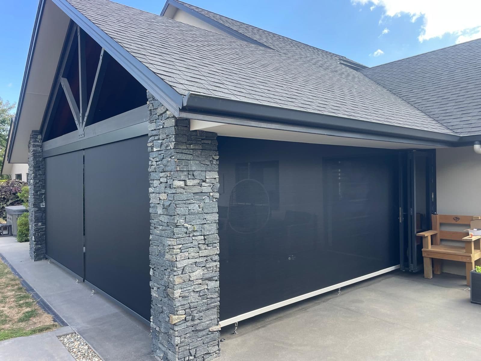Dark Omni outdoor screen blinds enclosing a stone-clad outdoor room