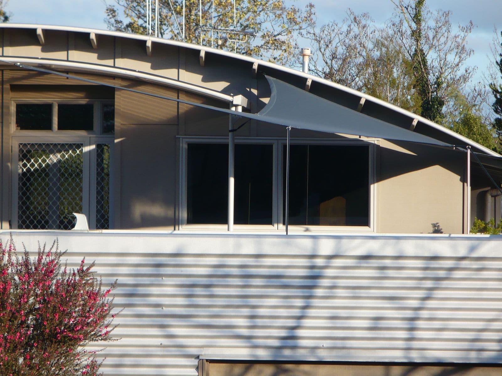 Dark shade sail against a curved architectural home