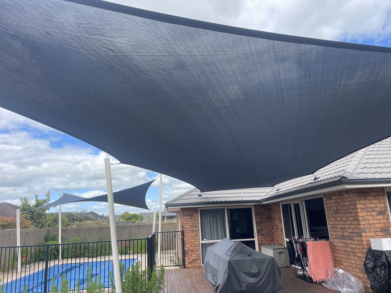 Grey shade sail shading a poolside deck