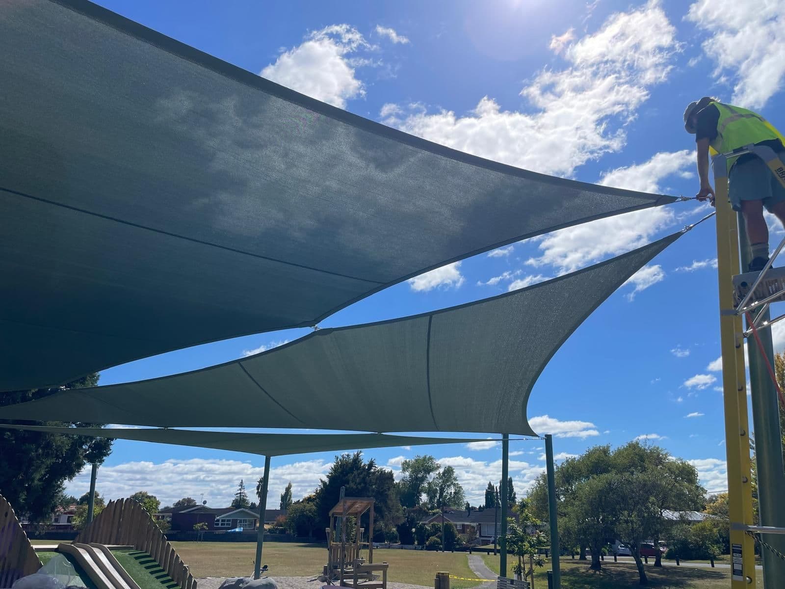 Outdoor Shade Solutions installer tensioning shade sails on site