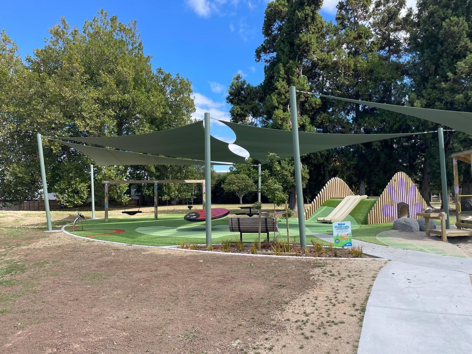 Green shade sails sheltering a park playground in the Waikato