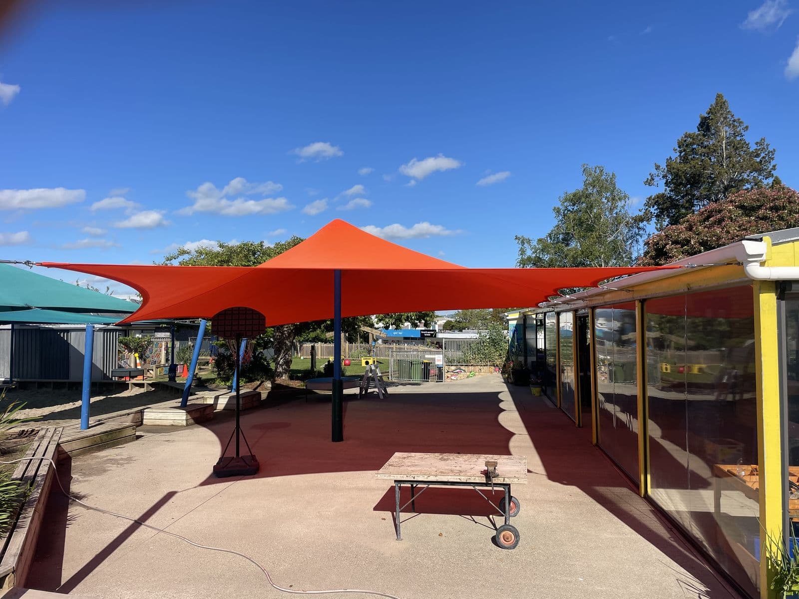 Large red shade sails over a school courtyard