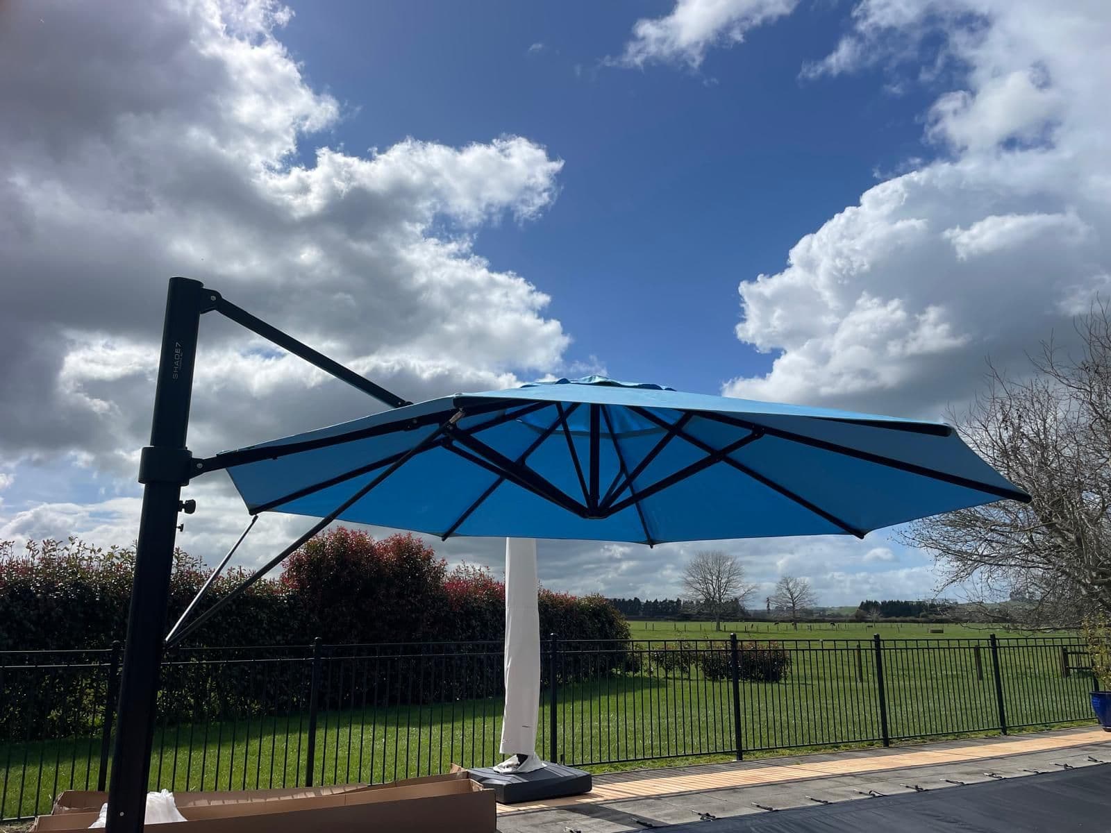 Blue cantilever umbrella opened against a big Waikato sky