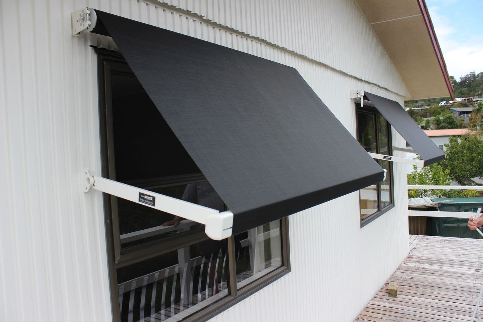 Black drop-arm window awning angled over a window