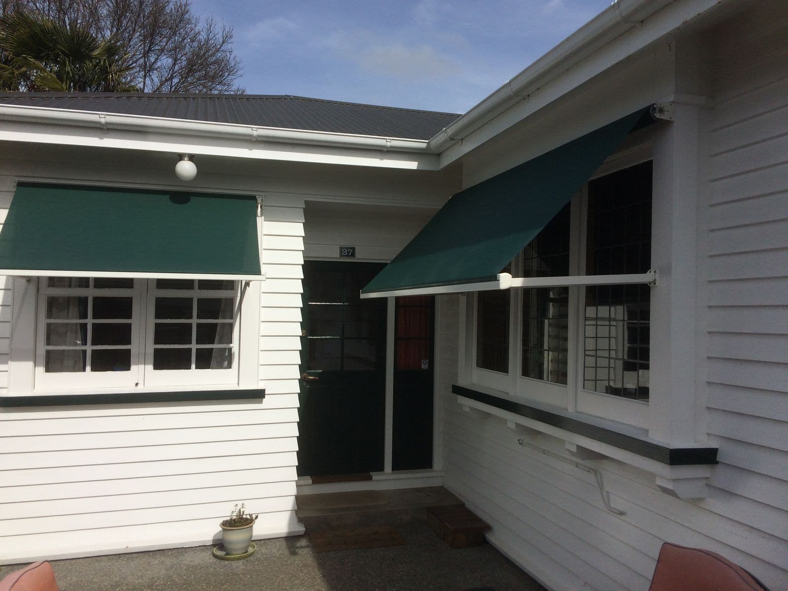 Green door awning on a white weatherboard villa