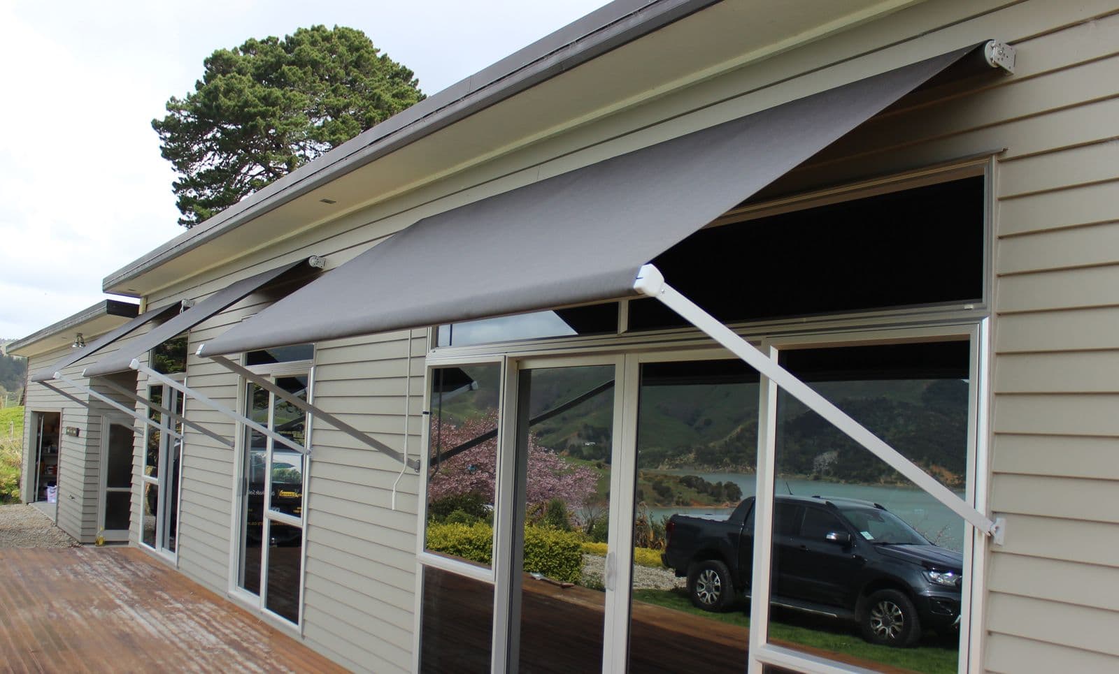 Grey Vertigo drop-arm awning over a home's deck
