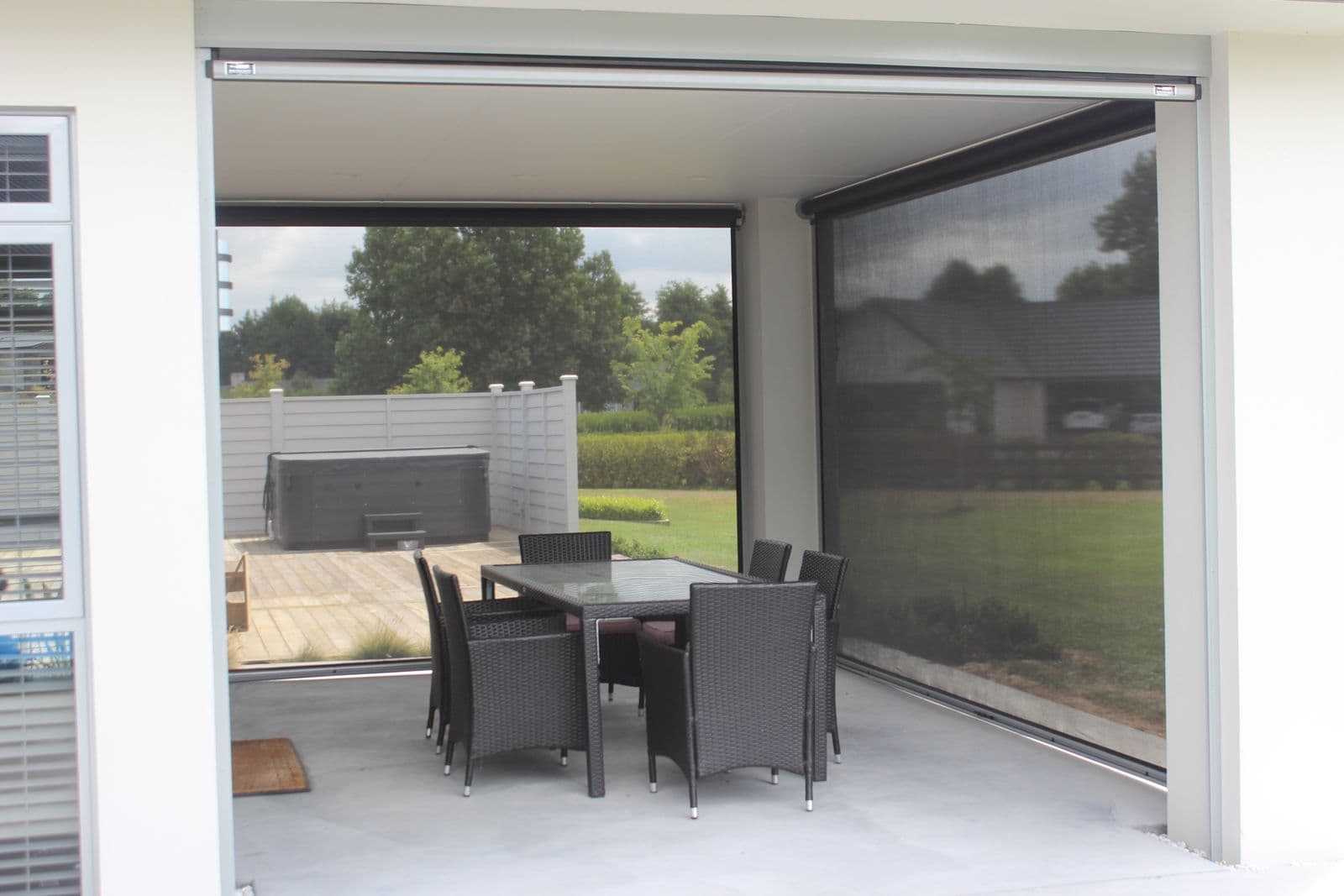 Classic black-mesh Ziptrak blind over an outdoor dining deck
