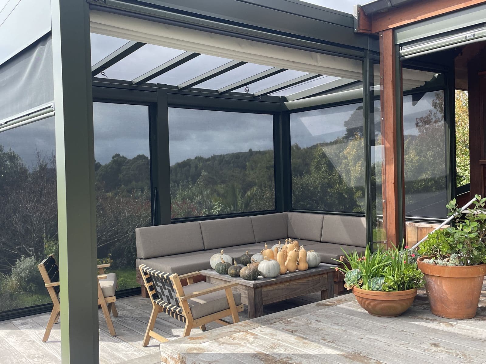 Ziptrak blinds enclosing a glass-roof pergola over an outdoor lounge