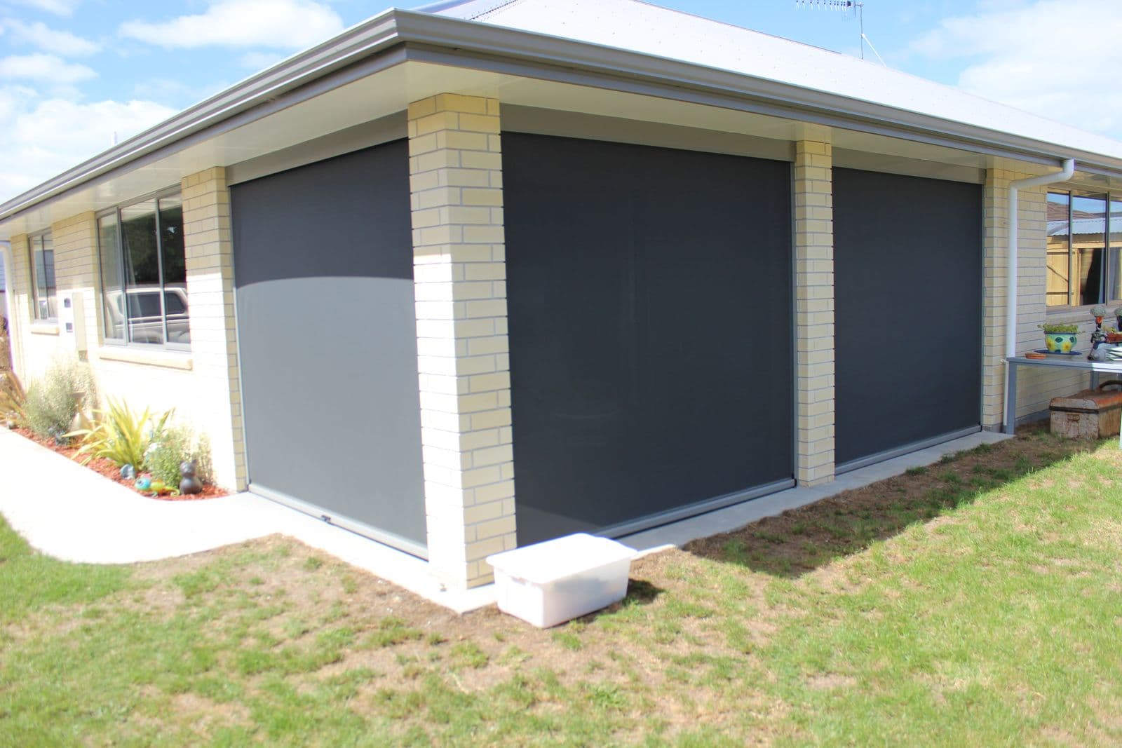 Grey Ziptrak screens wrapping the corner of a new home