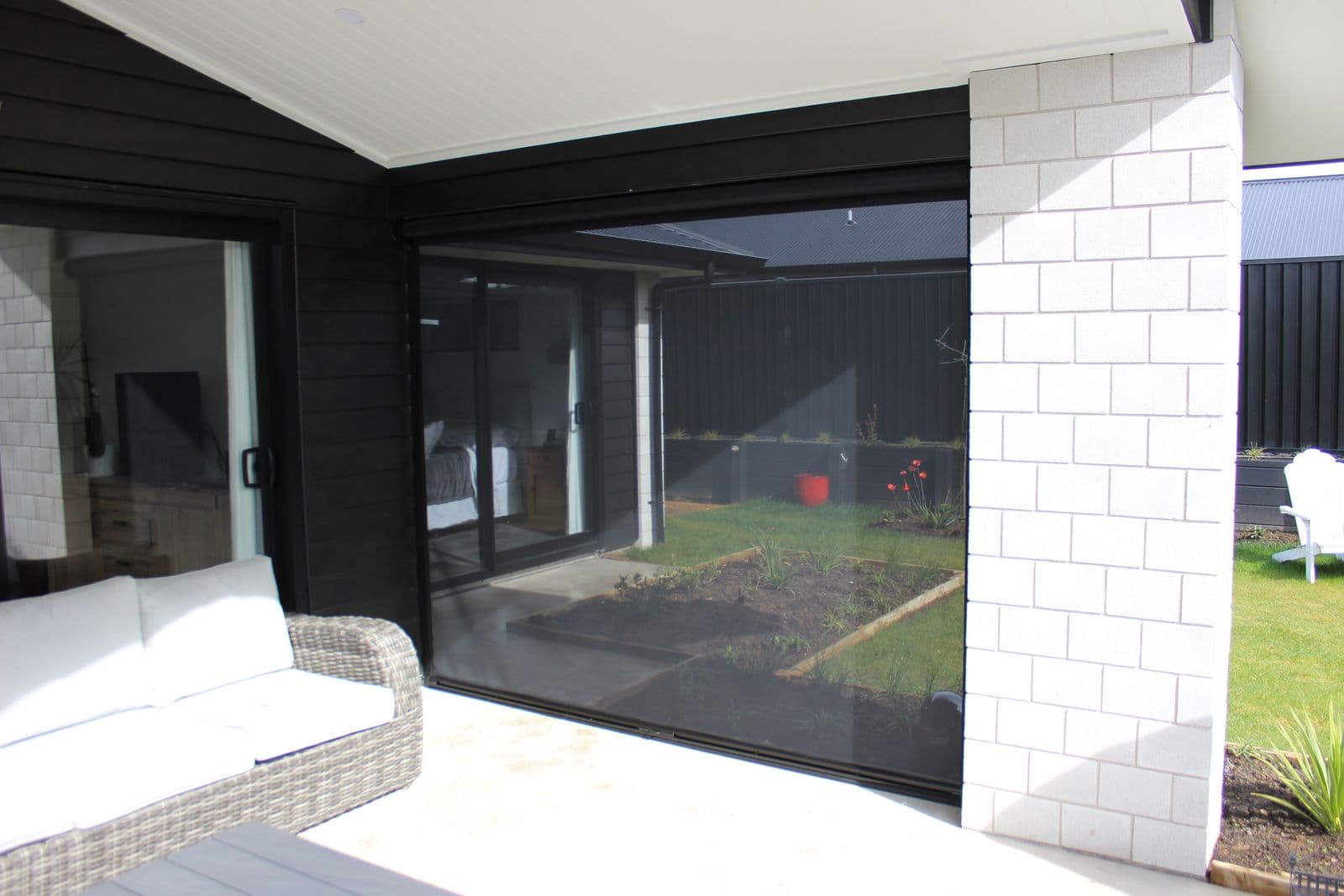 Corner Ziptrak blinds on a white-brick home patio