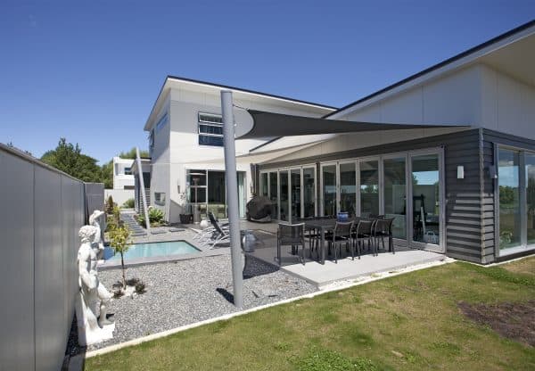 Grey custom shade sail spanning the patio of a contemporary two-storey house