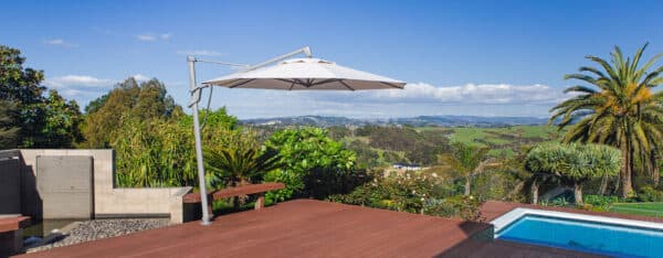 Shade7 Stellar cantilever umbrella in sand shading an outdoor dining setting