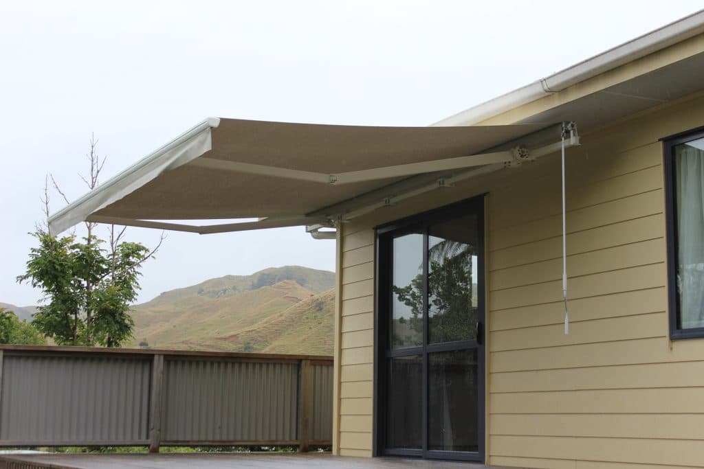 Folding-arm awning shading a paved outdoor entertaining area