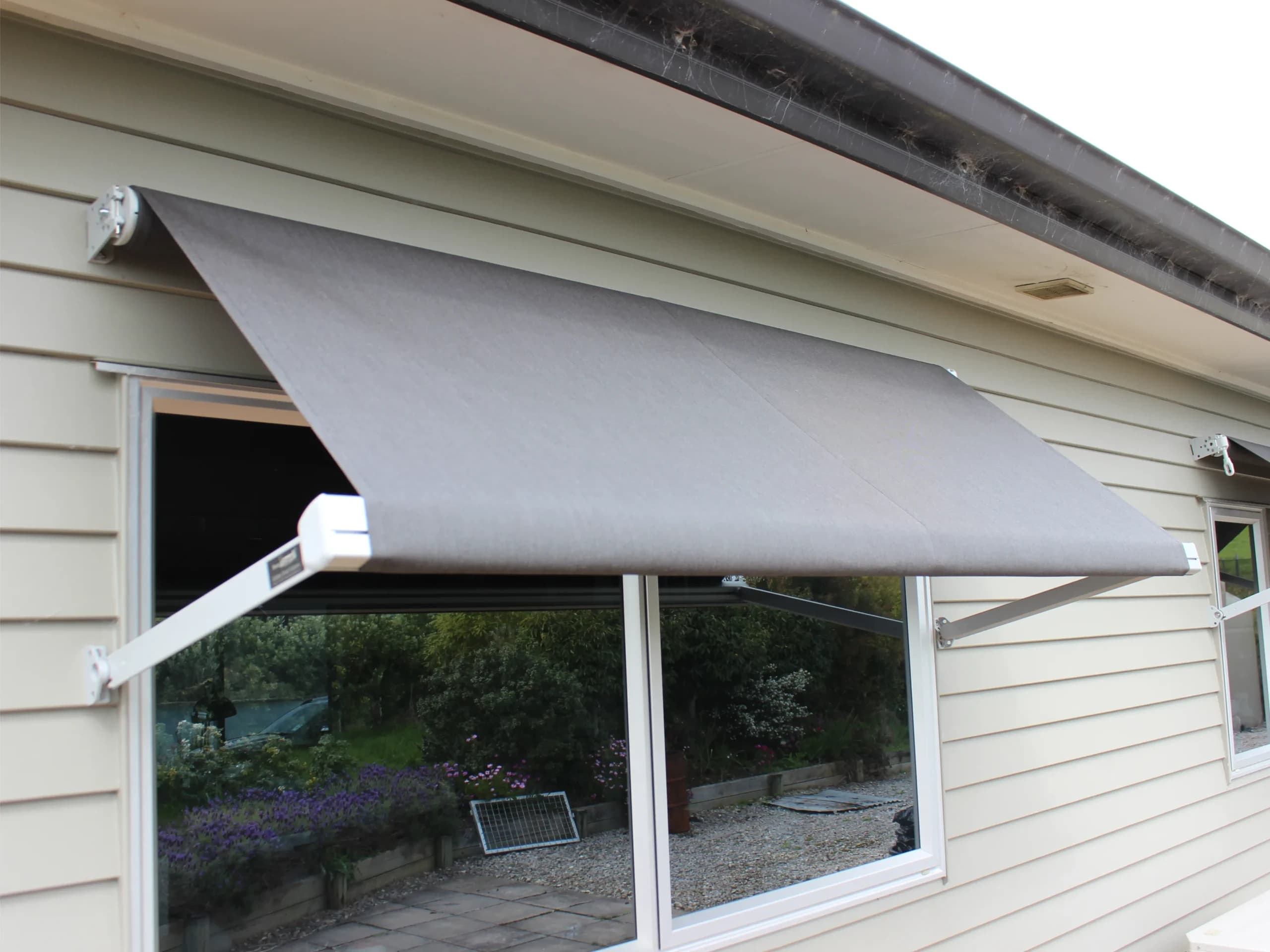 Grey Vertigo drop arm window awning on a Waikato home
