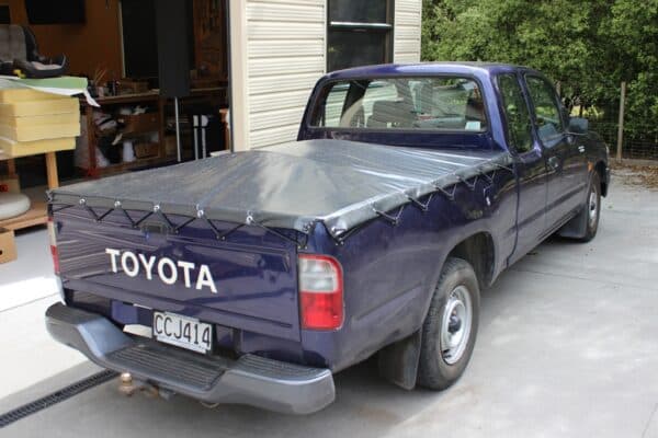Fitted cover over a barbecue on an outdoor bench