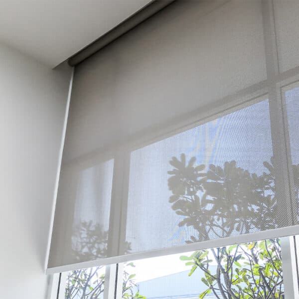Grey roller blind partially lowered over a corner window
