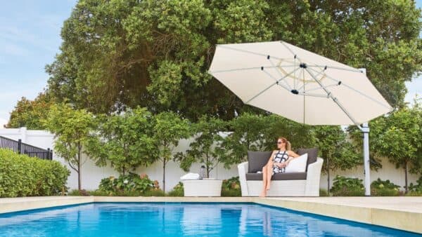 White Shade7 Riviera umbrella tilted over poolside loungers