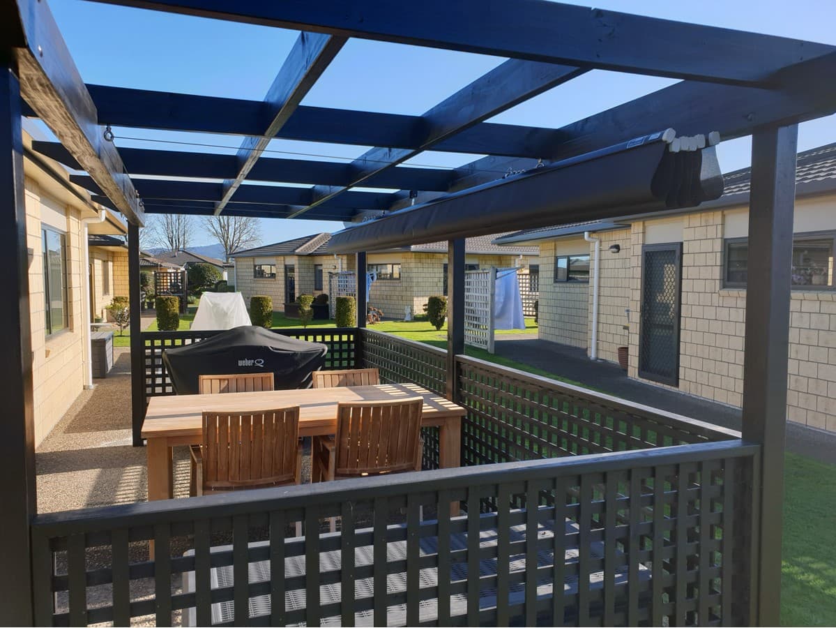 Wave shade canopy installed under a pergola over an outdoor dining area
